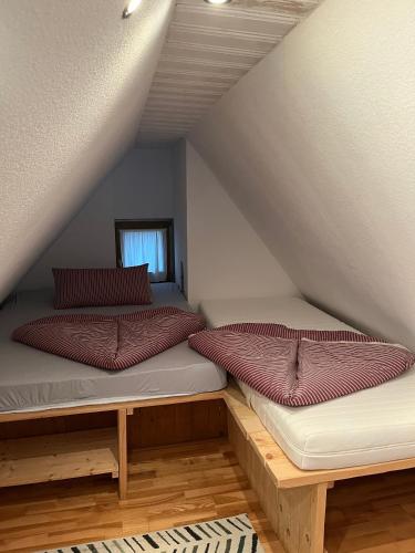 two beds in a attic with red pillows on them at Galeriewohnung mit Seeblick in Absberg