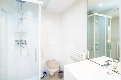 a white bathroom with a shower and a toilet at Appartement de charme - spa privé in Biarritz