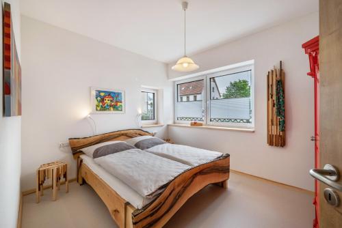 a bedroom with a wooden bed and two windows at Alb-Sonne Ferienwohnung in Sonnenbühl