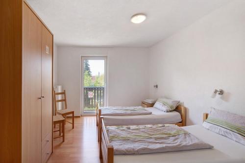 a bedroom with two beds and a window at Ferienwohnungen große Albferien in Heroldstatt