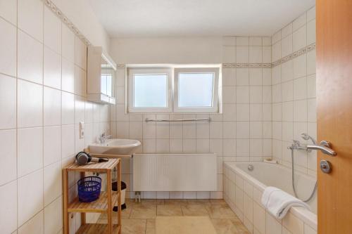 a white bathroom with a tub and a sink at Ferienwohnungen große Albferien in Heroldstatt