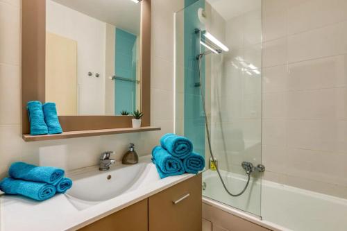 a bathroom with a sink and a shower with blue towels at Le Murmure pieds dans l'eau in La Grande Motte