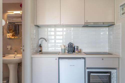 a kitchen with white cabinets and a sink at Panorama Apartments in Skoutari