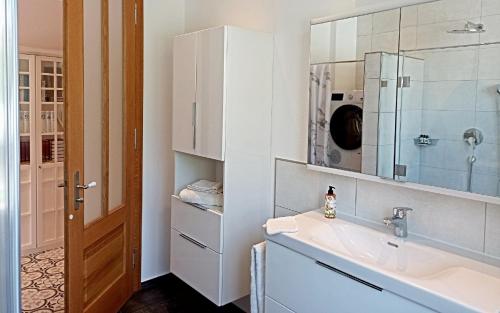 a white bathroom with a sink and a mirror at Villa Karlsbach in Teisendorf