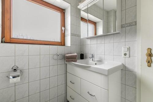 a white bathroom with a sink and a mirror at Ferienwohnung Davio in Lohe-Rickelshof
