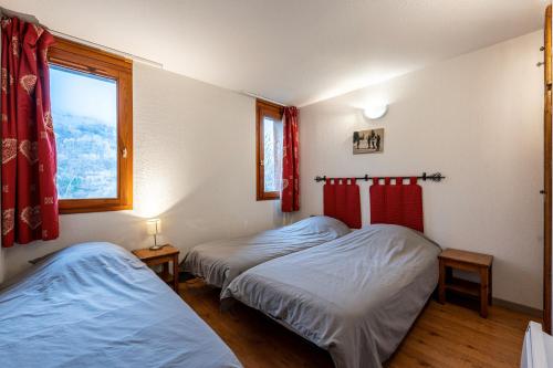 two beds in a room with a window at Valloire - Appartement avec piscine in Valloire