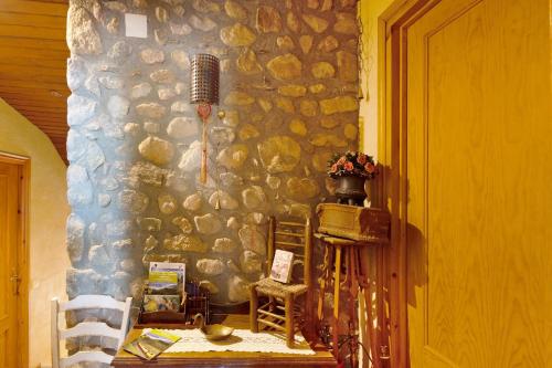 a room with a stone wall with a table and chairs at Mas Cal Gintó in Das
