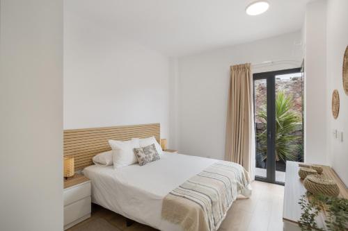 a white bedroom with a bed and a window at Yucas Villa 17 in San Bartolomé