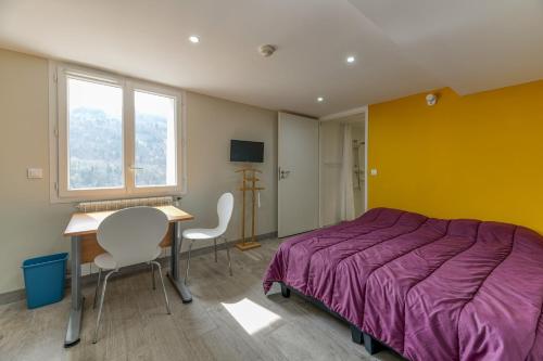 a bedroom with a bed and a table and chairs at Logis Les Forges in Arvillard