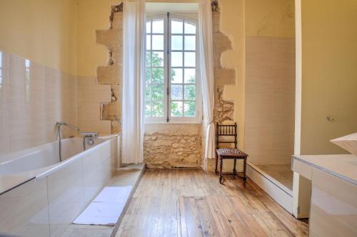 a bathroom with a tub and a window and a chair at Le Bel Prat in Domme
