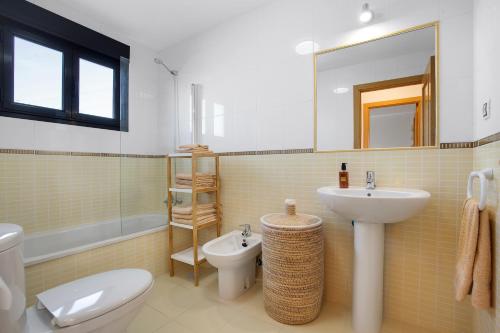 a bathroom with a sink and a toilet and a mirror at Sunny Home in Lajares