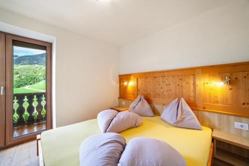a bedroom with a yellow bed with pillows and a window at Fichtenhof Wohnung Enzian in Tarces