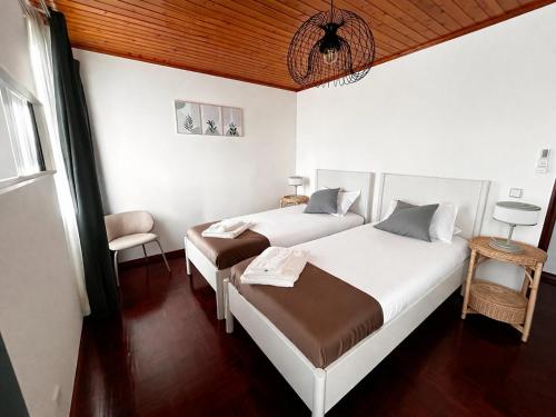 a bedroom with two beds and a chair at Ocidente House 2 in Santa Cruz das Flores