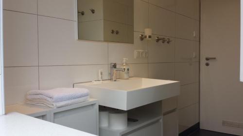 a white bathroom with a sink and a mirror at Ferienwohnung Birkenhof Alfsee in Rieste