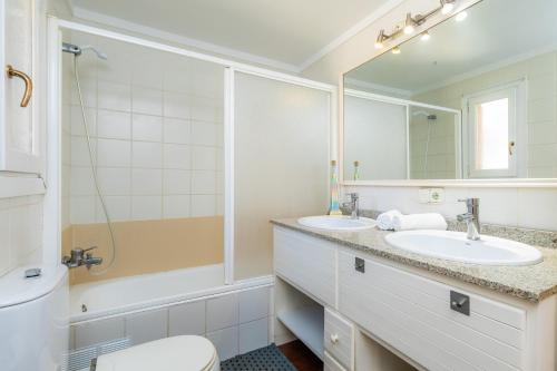 a bathroom with two sinks and a toilet and a mirror at Villa Paca in Cala Ratjada