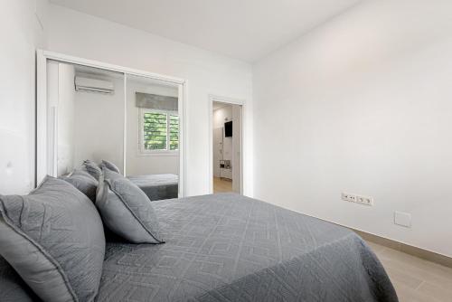 a white bedroom with a bed with gray pillows at Apartamentos Sealmar Moliere in Málaga