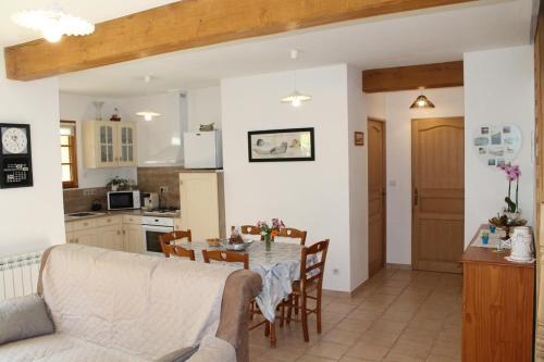 a kitchen and living room with a table and a couch at Gîte La Briqueterie 3 Épis in Quesnoy-le-Montant
