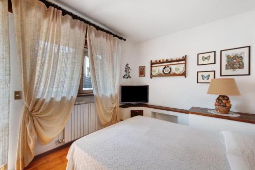 a bedroom with a bed and a window with a television at Monolocale Monti Pallidi in Domegge di Cadore