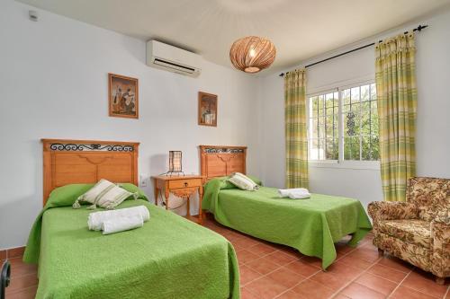 a bedroom with two green beds and a chair at Cortijo Los Ángeles Morea in Frigiliana