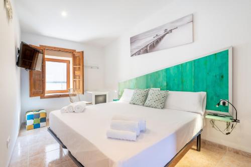 a bedroom with a white bed with a green wall at Cas Solleric in Petra