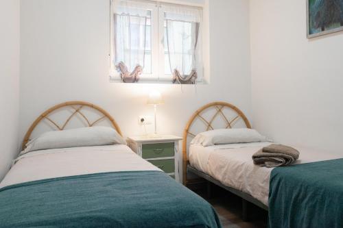 two beds in a small bedroom with a window at Apartamento Puertu Chicu in Llanes