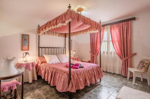 a bedroom with a canopy bed with pink sheets at Ca na Rossa in Campanet