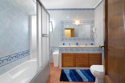 a bathroom with a tub and a sink and a toilet at Villa Guisado in Albufeira