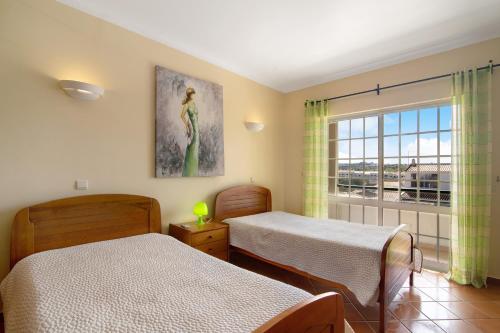 a bedroom with two beds and a window at Villa Guisado in Albufeira