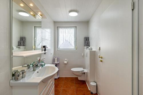 a white bathroom with a sink and a toilet at Apartment Ayleen in Boll