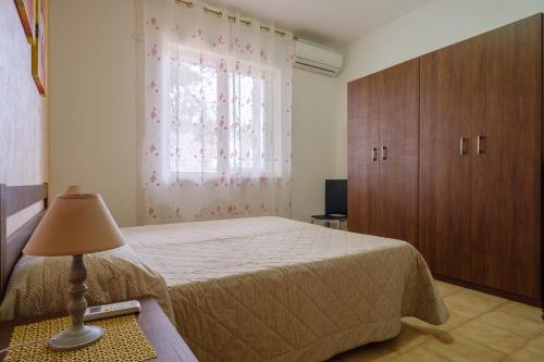 a bedroom with a bed and a window and a lamp at Villetta del Salento 1 in Racale