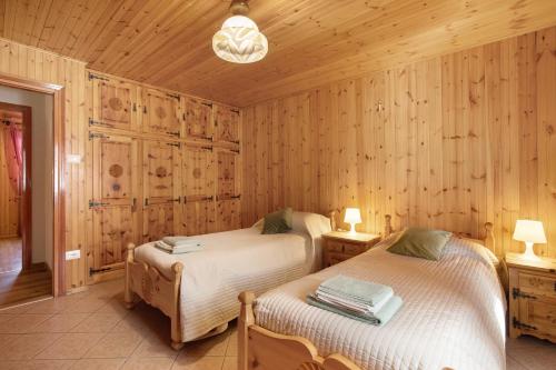 two beds in a room with wooden walls at La Maison du Bonheur Lillaz in Cogne