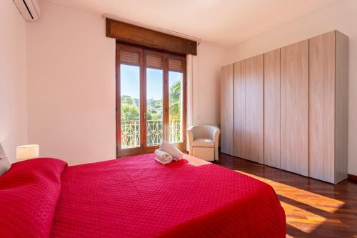 a bedroom with a red bed and a large window at Villa Stella in Marsala