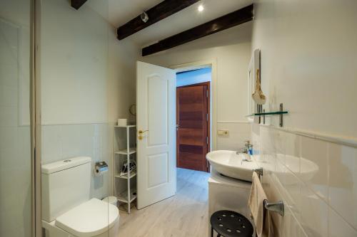 a white bathroom with a toilet and a sink at Apartamento Can Roses in Moscari