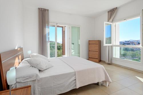 a white bedroom with a large bed and windows at Villa Marconi Apartment 7 in Golfo Aranci