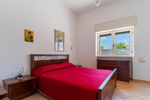 a bedroom with a red bed and a window at Villa Tina a Torre Lapillo in Torre Lapillo