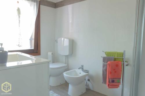 a white bathroom with a toilet and a sink at The Comfort Apartment in Montagnana