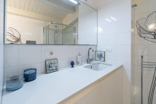 a white bathroom with a sink and a mirror at Elvi Suite Vista Mare Marzamemi in Marzamemi