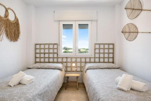 two beds in a room with a window at Casa Noria in Vejer de la Frontera