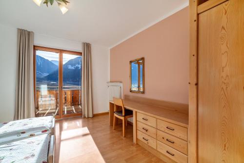 a bedroom with a desk and a bed and a window at Langstein Wohnung Rose in Coldrano