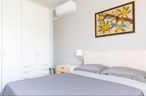a white bedroom with a bed and a picture on the wall at Trilocale colline di Bardolino in Bardolino