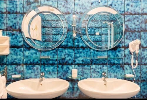 a blue tiled bathroom with two sinks and mirrors at Trilocale colline di Bardolino in Bardolino