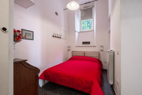 a red bed in a white room with a window at Al Cornelio in Orvieto