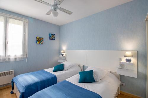 two beds in a room with blue walls at Lumineux Le Bugue in Le Bugue