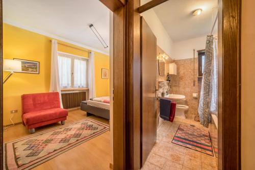 a living room with a red chair and a bathroom at Apartement Oase in Lana