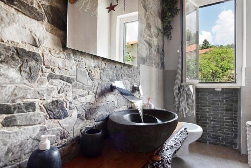 a bathroom with a sink in a stone wall at Barcollo House - Piscina nel verde in Stella