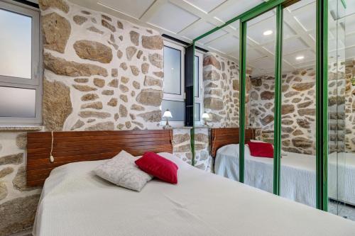 a bedroom with two beds and a stone wall at Quinta Santa Marinha in Arcos de Valdevez
