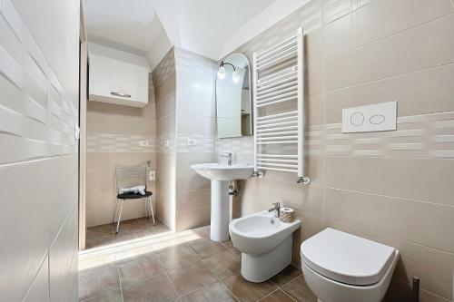 a white bathroom with a toilet and a sink at La Castellana in Monte SantʼAngelo