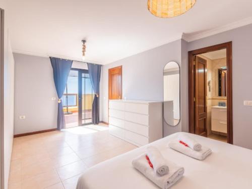 a white bedroom with a white bed and a mirror at Costa Fortuna in Poris de Abona
