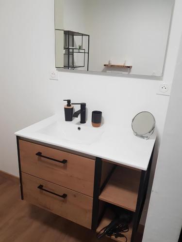 a bathroom vanity with a white counter and a mirror at Le Ty Gîte - Sud Morbihan in Théhillac
