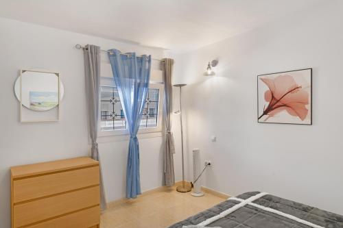 a bedroom with a bed and a window with blue curtains at Casa Paula - 25 in Arinaga